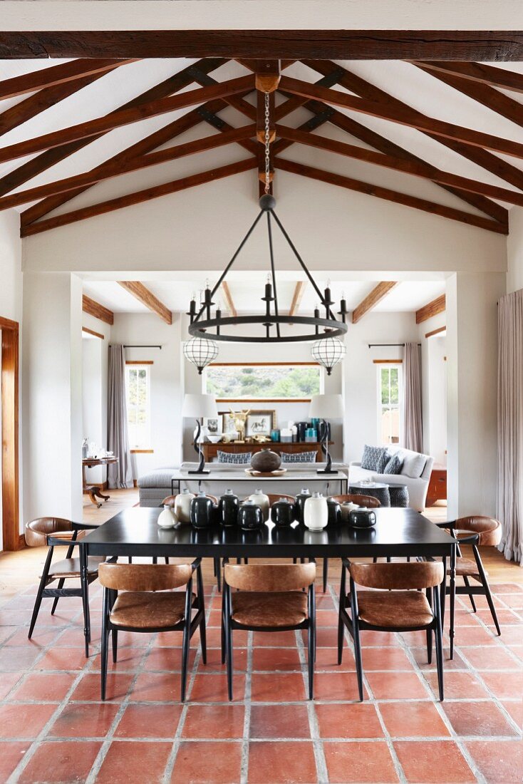 Schwarzer Esstisch und Stühle auf Terrakottafliesenboden in offenem Wohnraum