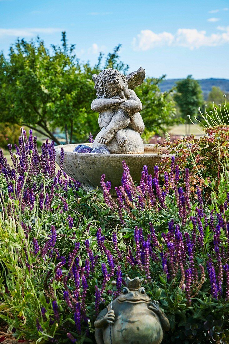 Angel figure in the fountain and frog prince in the lavender bed