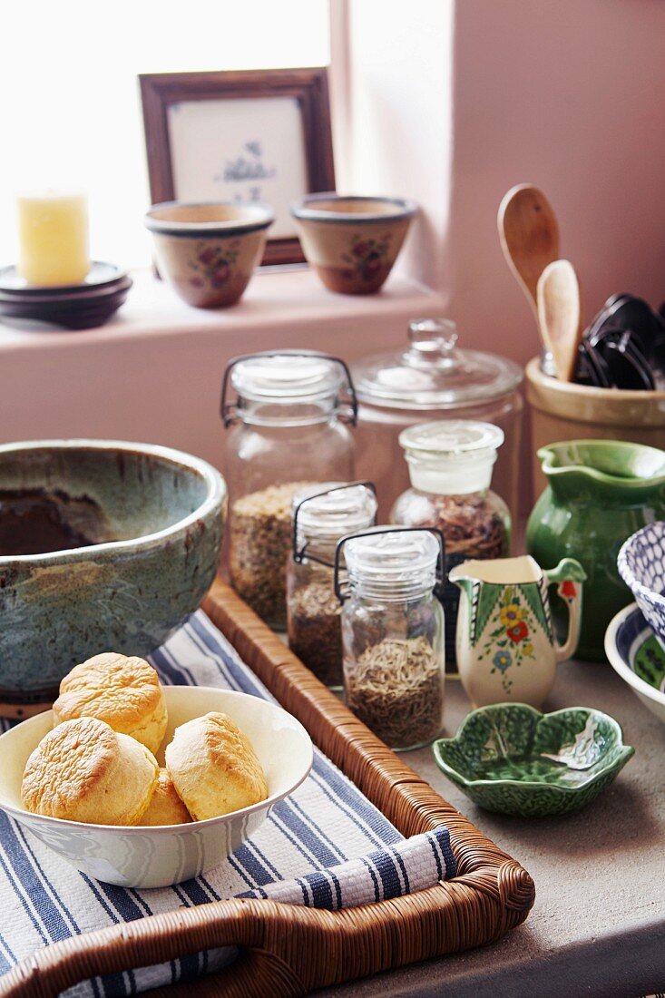 Storage jars, ceramic crockery and pastries on wicker tray