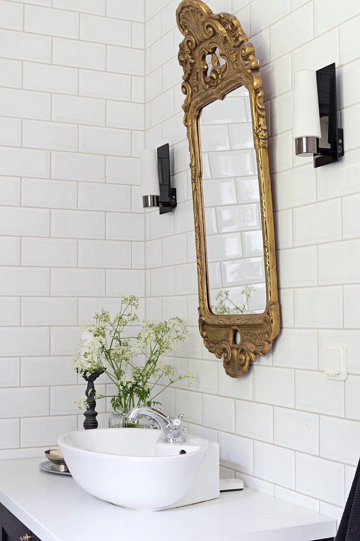 White countertop sink below gilt-framed mirror in vintage-style bathroom