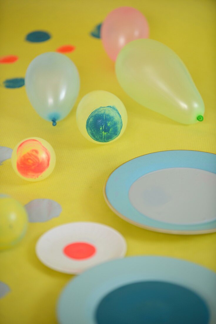 Teller mit Farben und Luftballons mit Farbtupfen