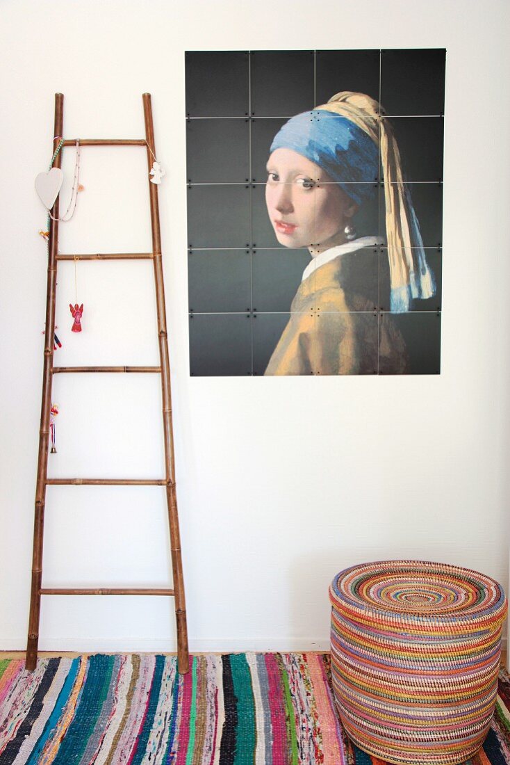 Frauenportrait an weisser Wand neben dekorierter Leiter auf buntem Flickenteppich