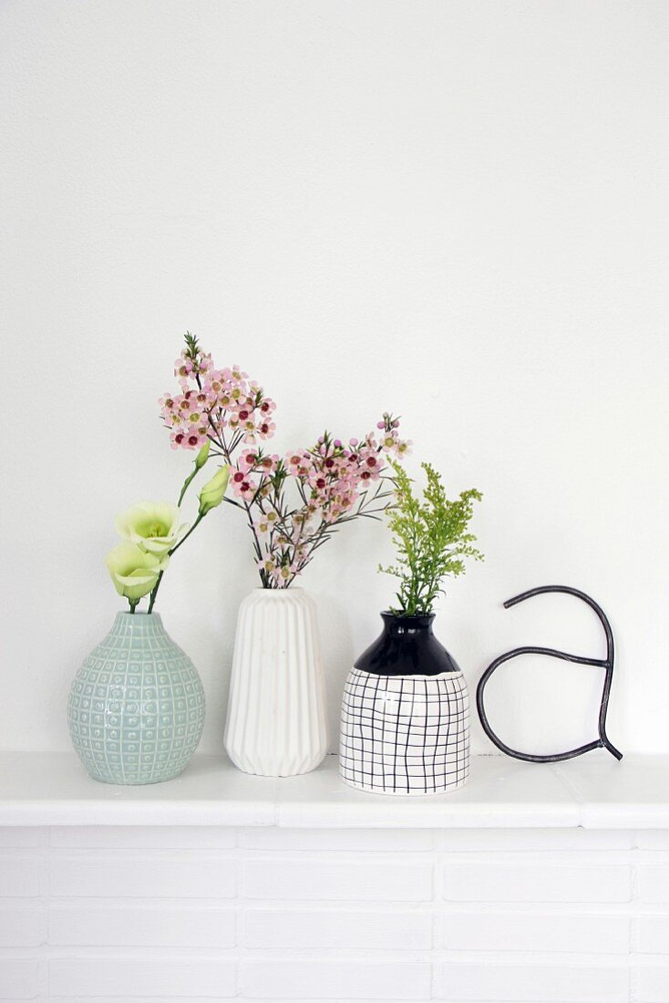 Retro arrangement of vases and flowers on white mantelpiece