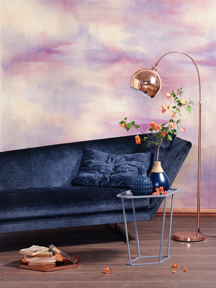 Sofa, side table and copper standard lamp against wall marbled in pink and purple