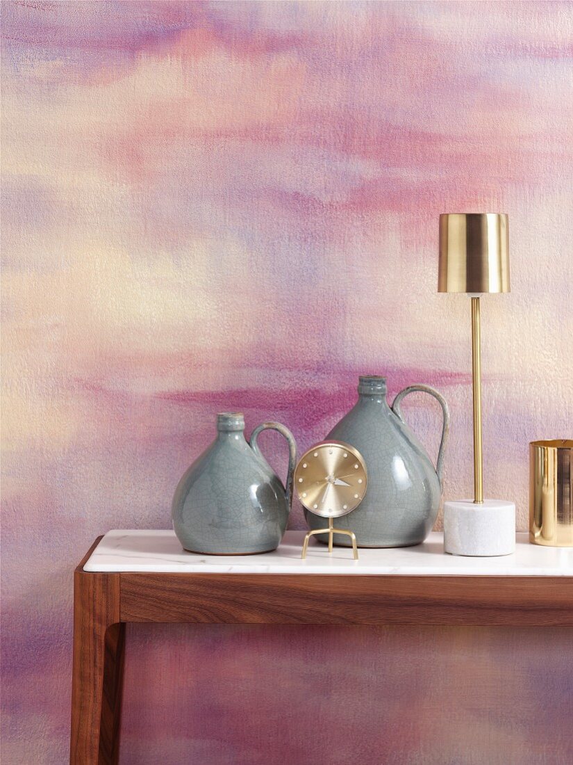 Retro vases and brass table lamp against wall marbled in pink and purple