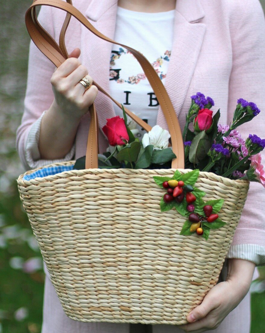 Frau hält Korbtasche mit blühenden Schnittblumen