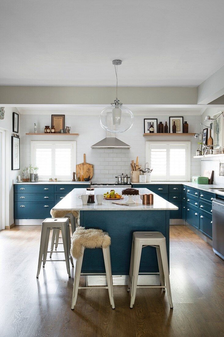 Landhausküche mit blauen Unterschränken und freistehende Theke mit Klassiker Barhocker aus Metall