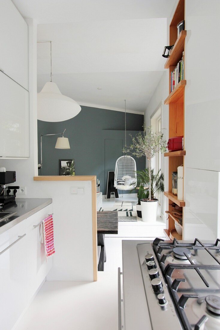 Gas cooker and white kitchen counter in open-plan interior with hanging chair in front of grey wall in background