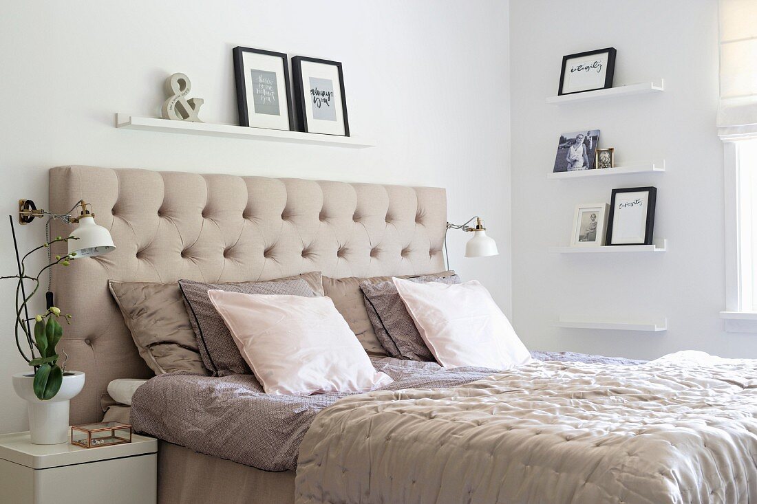 Doppelbett mit beigefarbenem, kaptioniertem Betthaupt und Wandboards in weißem Schlafzimmer