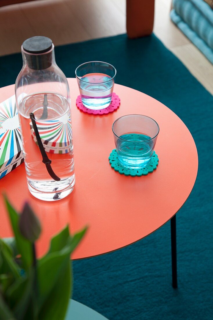 Glasses and bottle on water on round red side table
