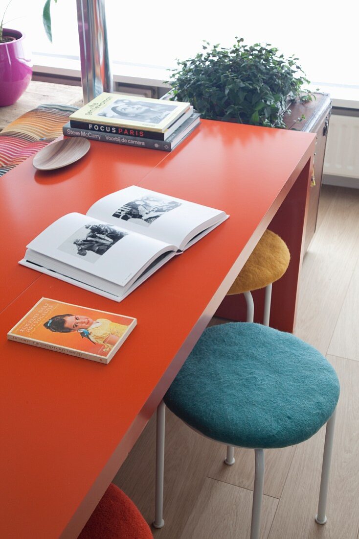 Mit Filz bezogene Hocker unter einem orangefarbenen Tisch