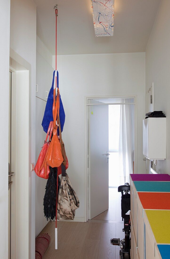 Von der Decke hängendes Seil als Garderobe mit Handtaschen