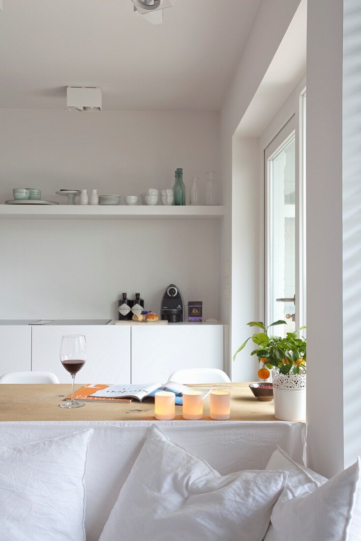 Blick über weißem Sofa mit Kissen auf Esstisch und Küchenzeile