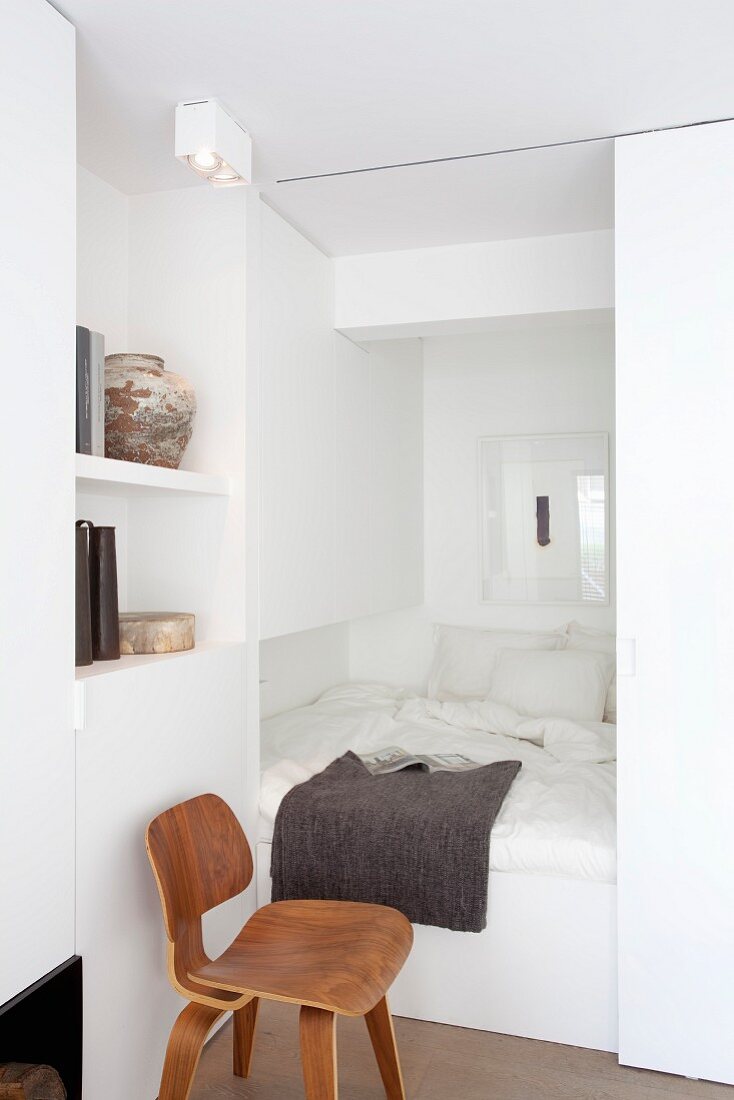 White cubby bed with sliding door in small apartment