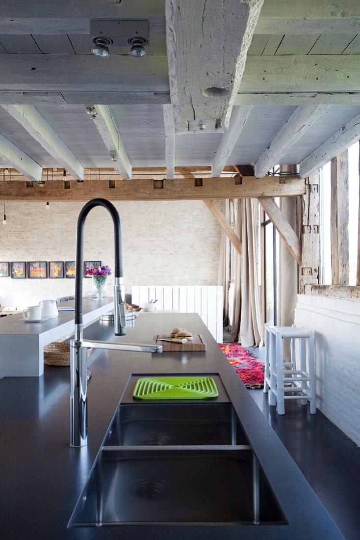 Kücheninsel mit Designer-Spülbecken und Armatur in umgebauter Scheune mit rustikaler Holzbalkendecke