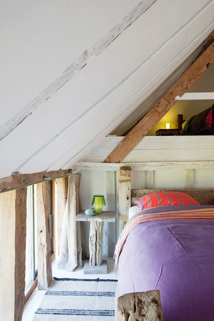 Rustic wooden double bed in attic bedroom