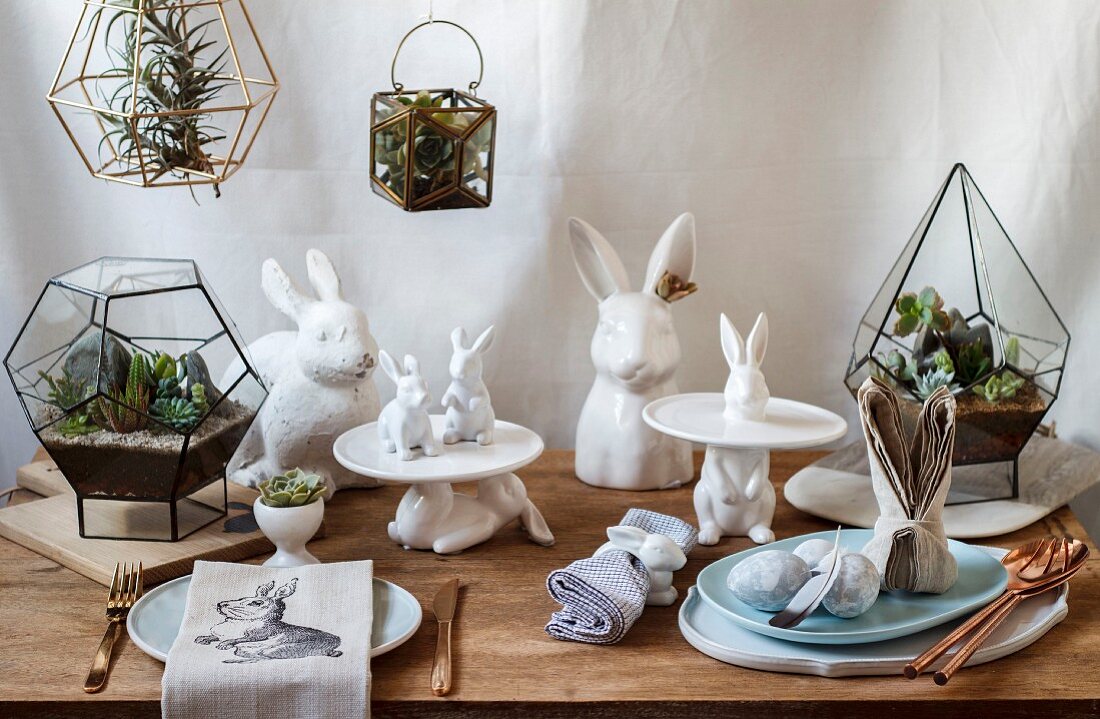 Österliche Tischdekoration mit Hasenfiguren und Mini-Terrarium mit Sukkulenten