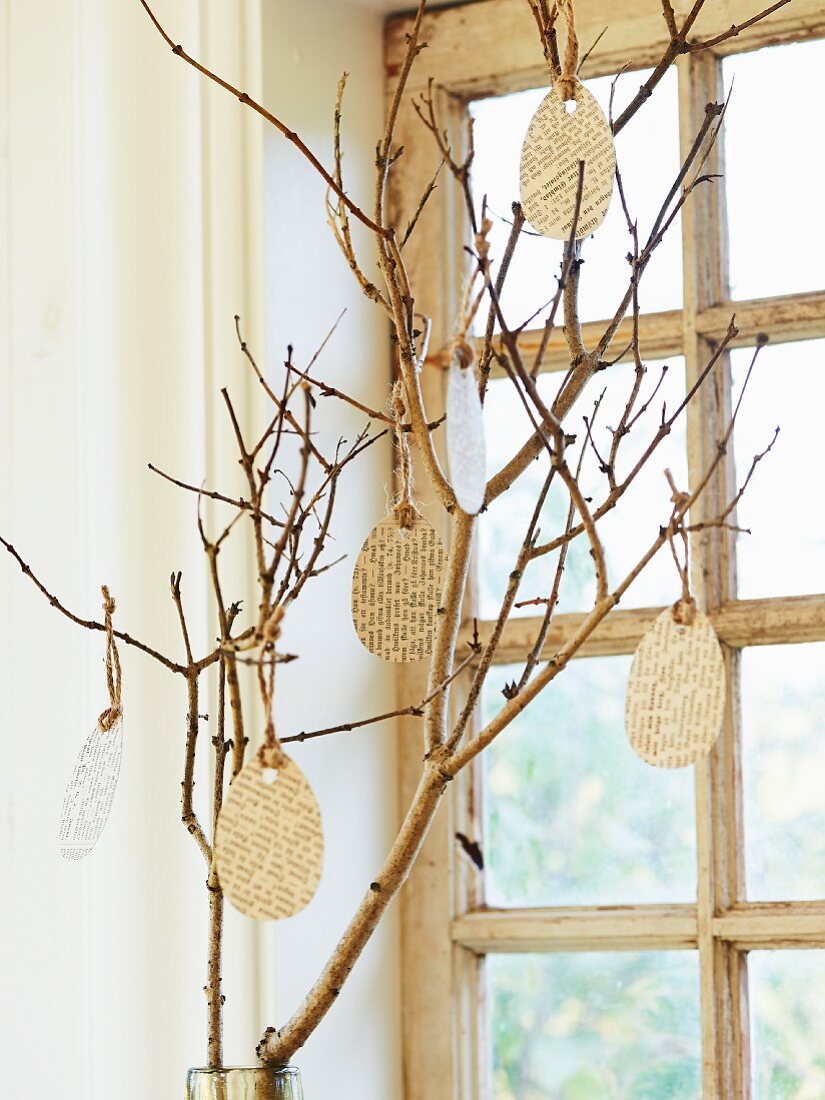 Paper Easter eggs hung from branch in front of window