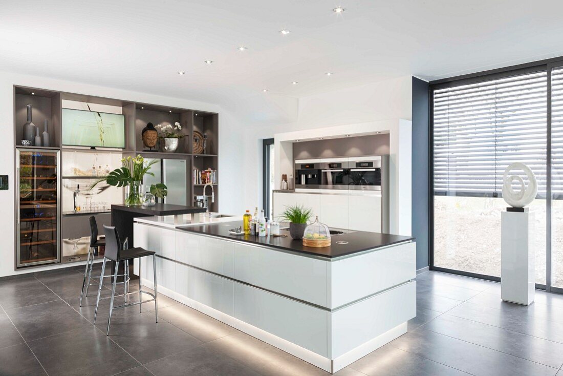 weiße Kücheninsel mit Sockelbeleuchtung in offener Designerküche