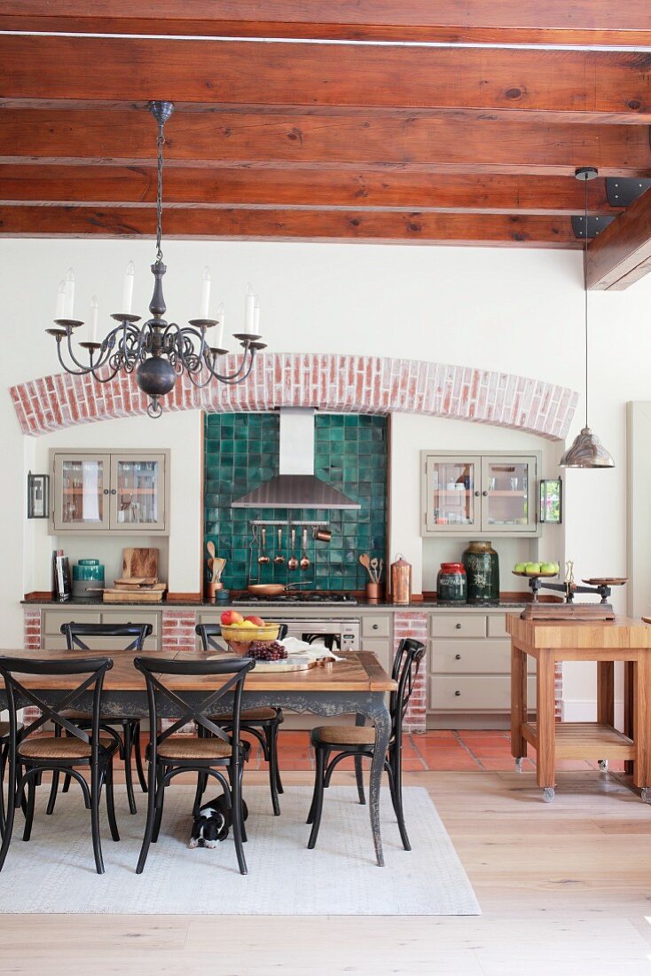 Küchenzeile im Landhausstil und Essbereich in offener Küche mit Holzbalkendecke