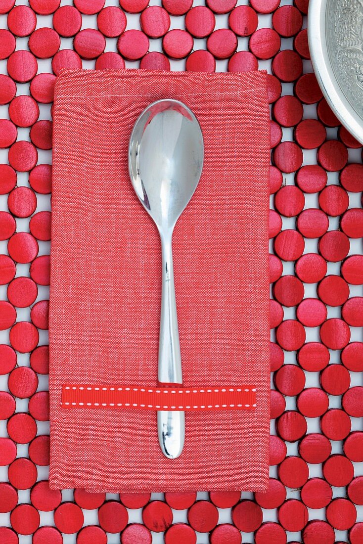 Spoon on red linen napkin and table mat made from red-painted wooden discs