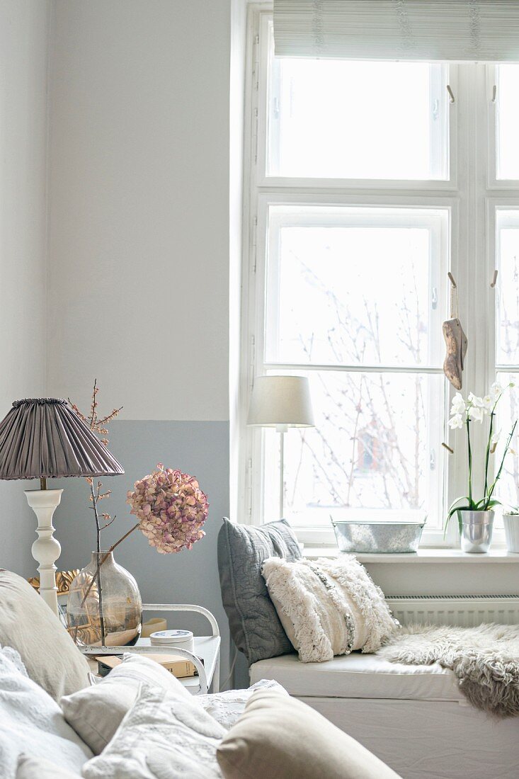 Cushions on white bench in corner of comfortable feminine bedroom