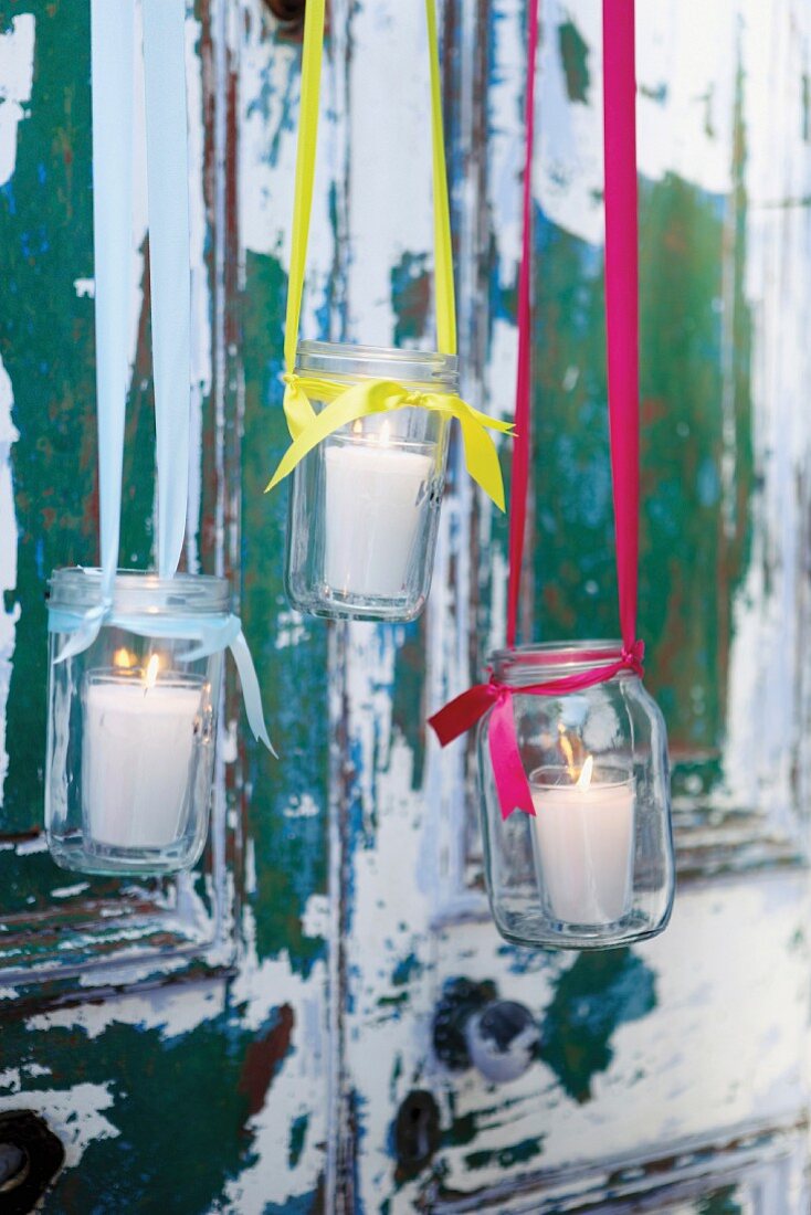 Candle lanterns made from preserving jars hung from colourful ribbons