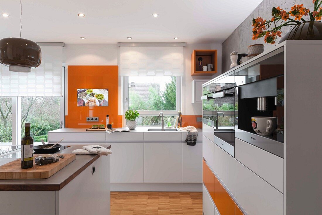 Moderne, offene Küche in Weiß mit orangefarbenen Farbakzenten