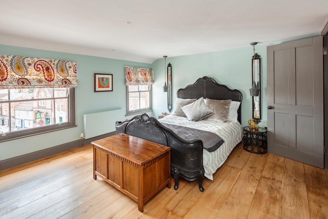 Nostalgisches Bett mit Korbgeflecht und Holztruhe in renoviertem Schlafzimmer mit Eichenholzfussboden
