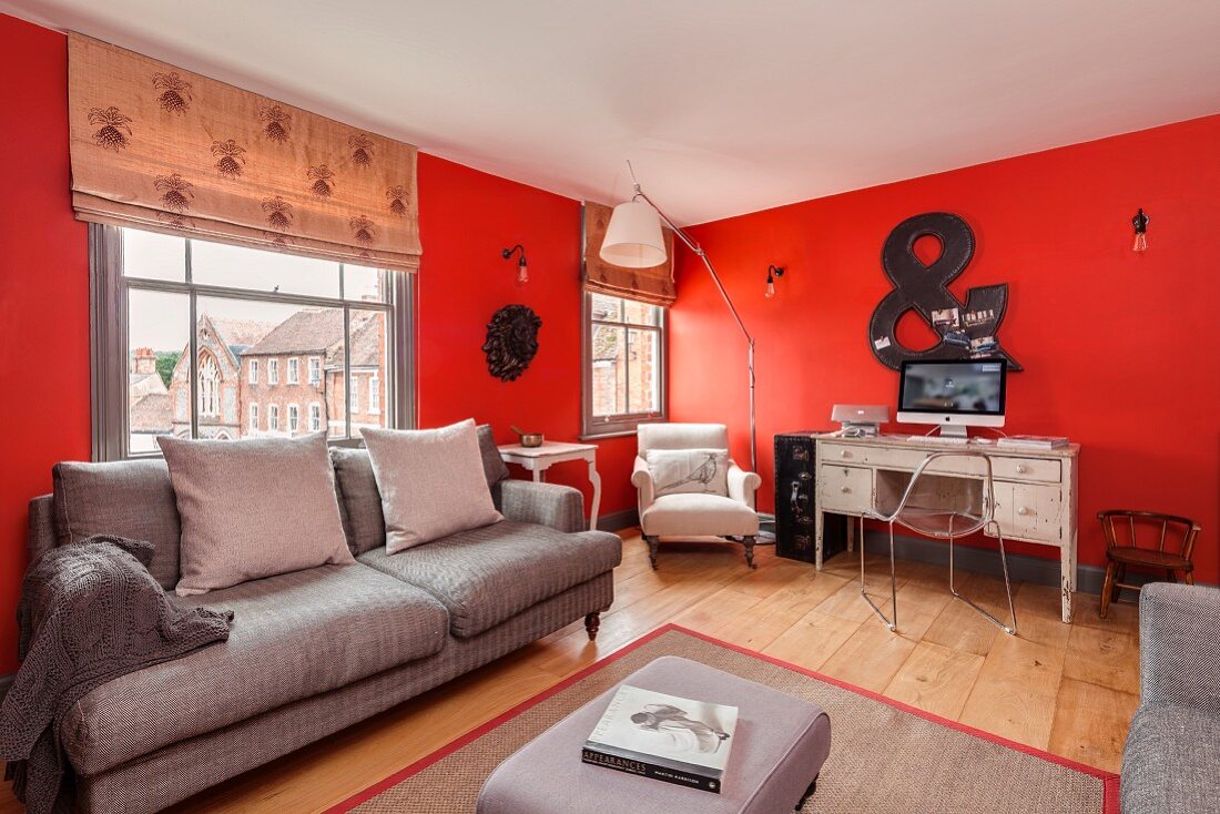 Lounge furniture and desk against red walls in renovated period apartment