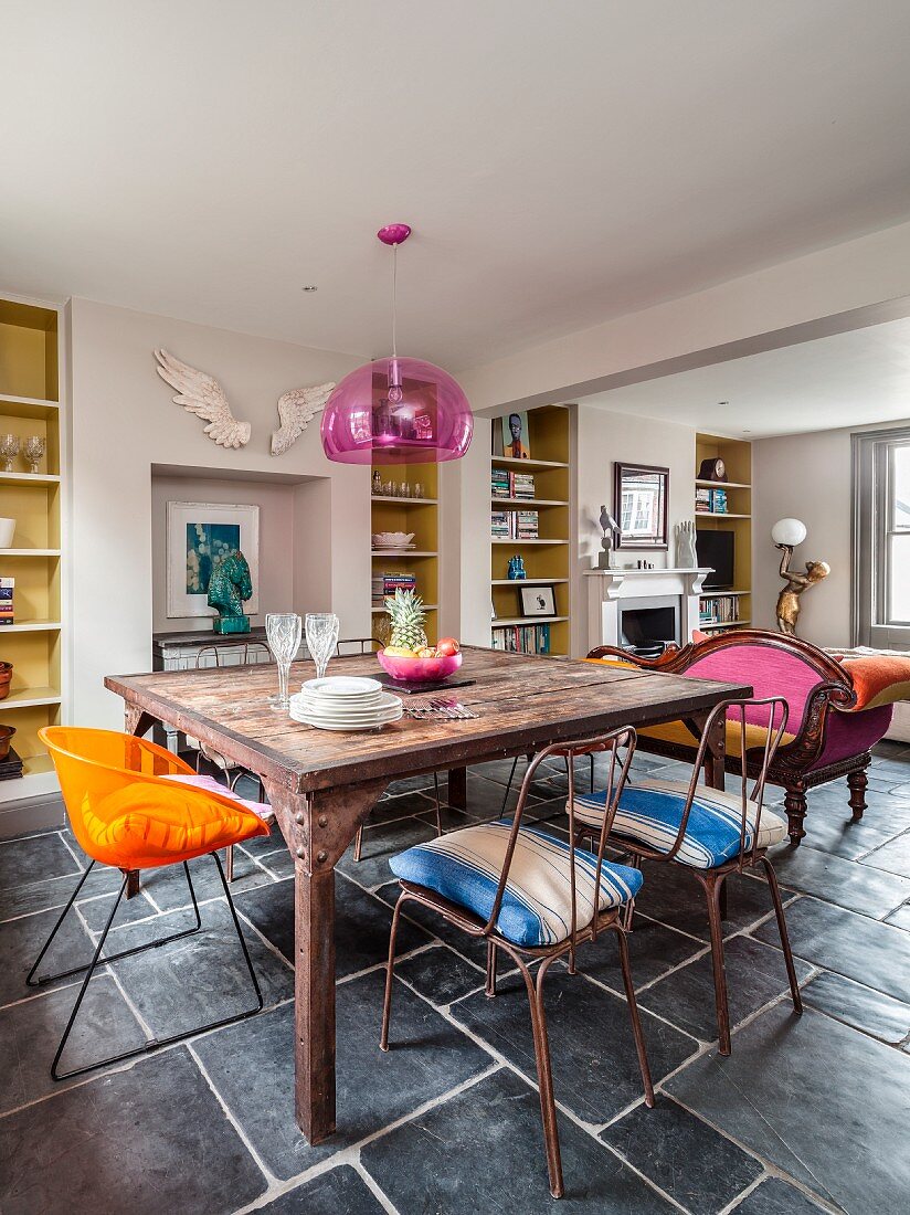 Vintage dinning table, metal chairs and retro chair in open-plan living area with fitted shelving