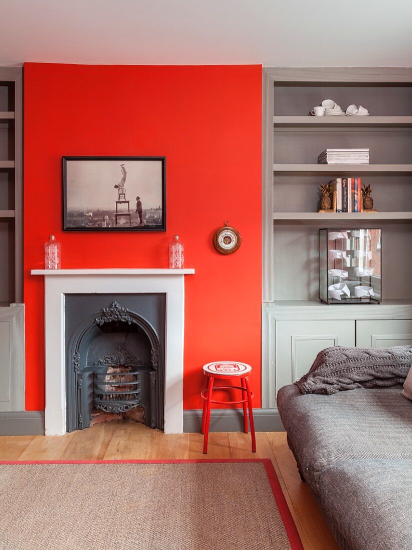 Vintage fireplace in red chimney breast flanked by grey fitted shelving
