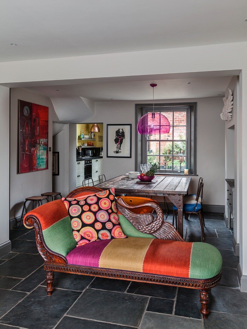 Art Nouveau chaise longue with colourful upholstery and scatter cushions in front of dining area