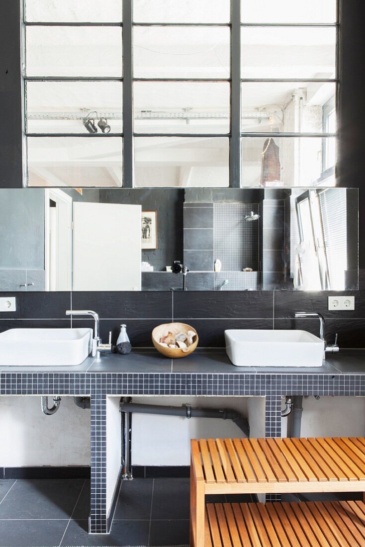 Twin countertop sinks in minimalist bathroom of loft apartment with industrial interior window