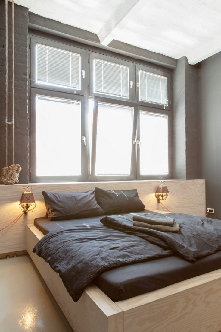 Custom double bed below window in minimalist bedroom