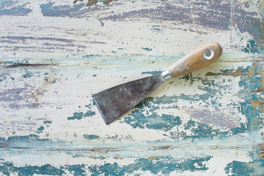 Spatula on wooden surface with peeling paint
