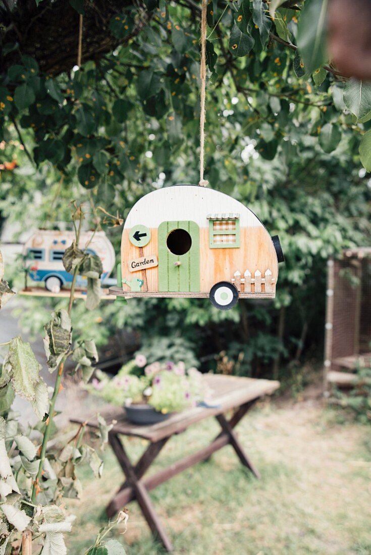 Vogelhaus in Form eines Campingwagens an einem Baum