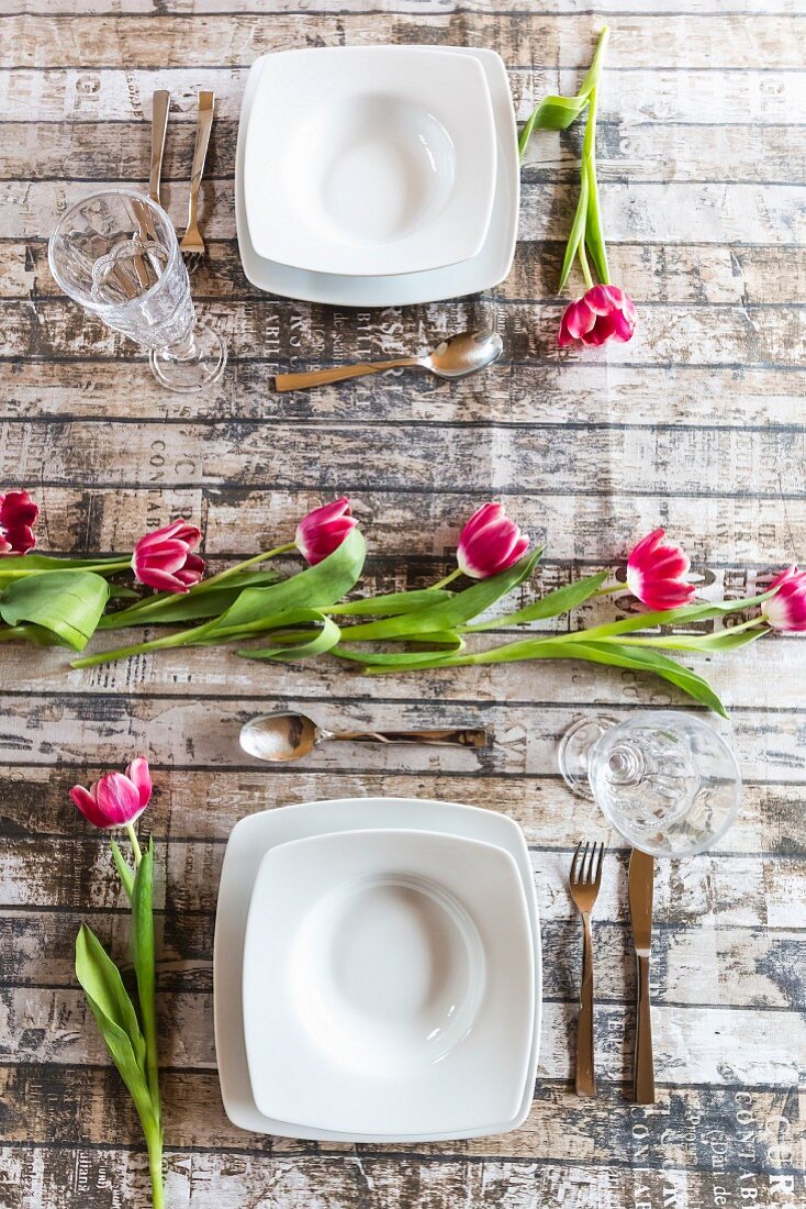 Zwei Gedecke auf frühlingshaftem Tisch mit Tulpen