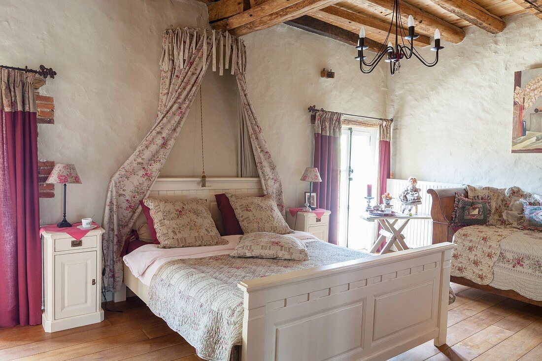 Bed with bed crown and rose-patterned textiles in romantic bedroom