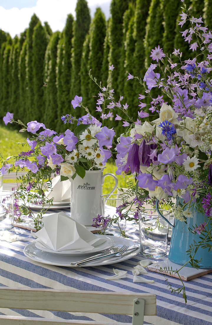 Vases of flowers on garden table festively set in blue and white