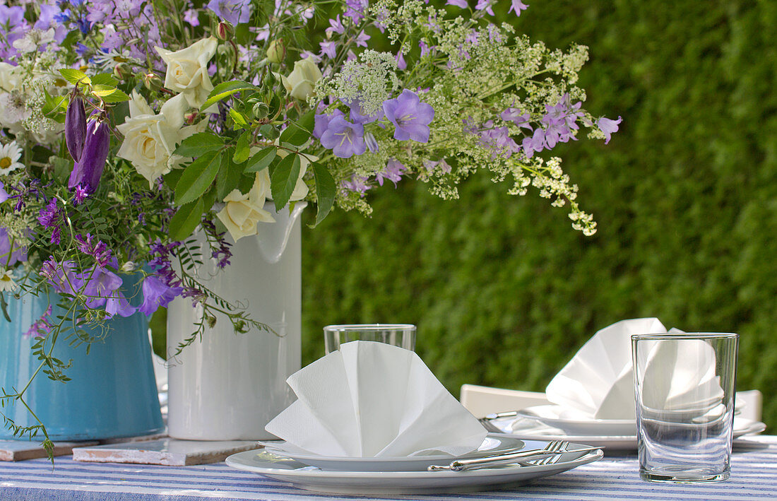 Blau-weißer Blumenstrauß auf festlich gedecktem Gartentisch