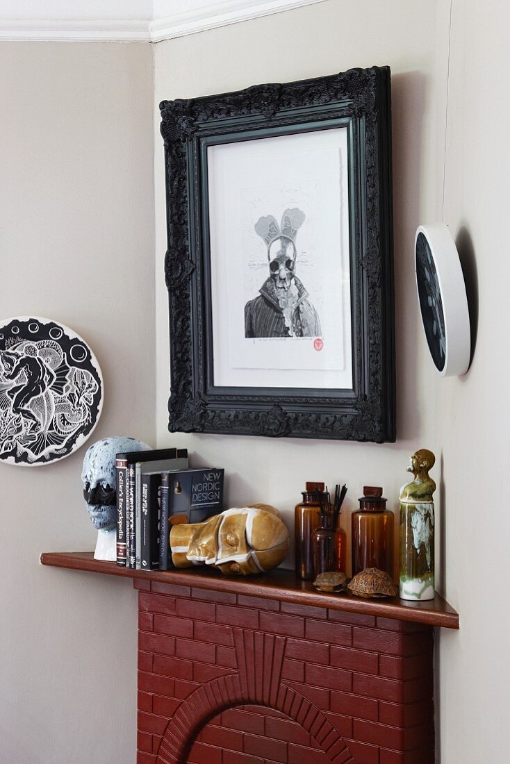 Modern graphical artwork in black frame above ornaments on mantelpiece