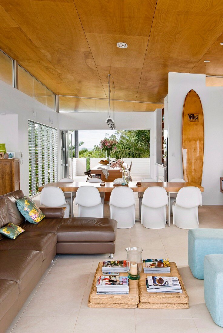 Offener Wohnraum mit gemütlicher Lounge, weißen Stuhlklassikern um langen Esstisch