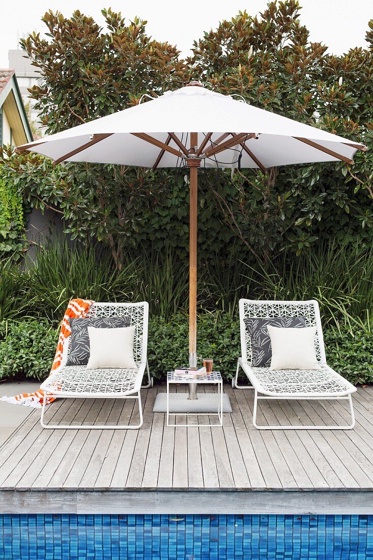 Two sun loungers under a white parasol by the pool