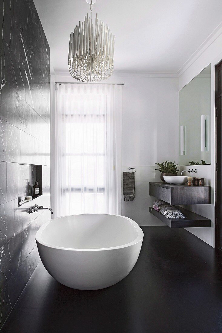 Elegante, frei stehende Badewanne im Bad mit schwarzem Boden