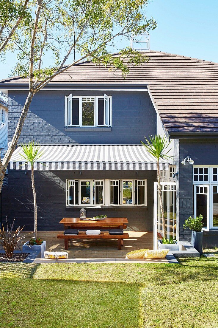 House with garden and patio under a striped awning