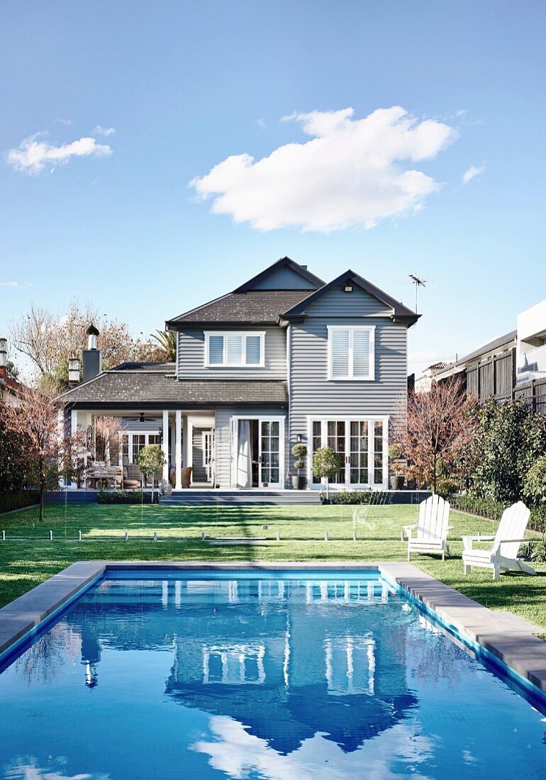 Haus und blauer Himmel spiegeln sich im Swimmingpool im Garten