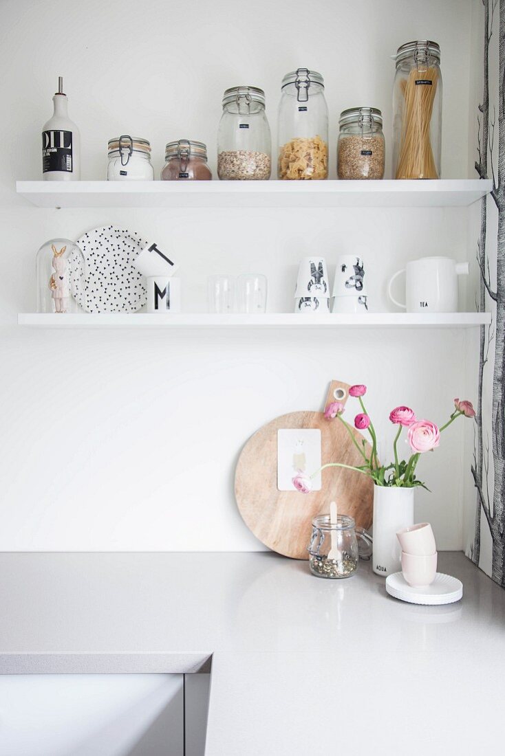 Storage jars and crockery on white shelves above kitchen counter