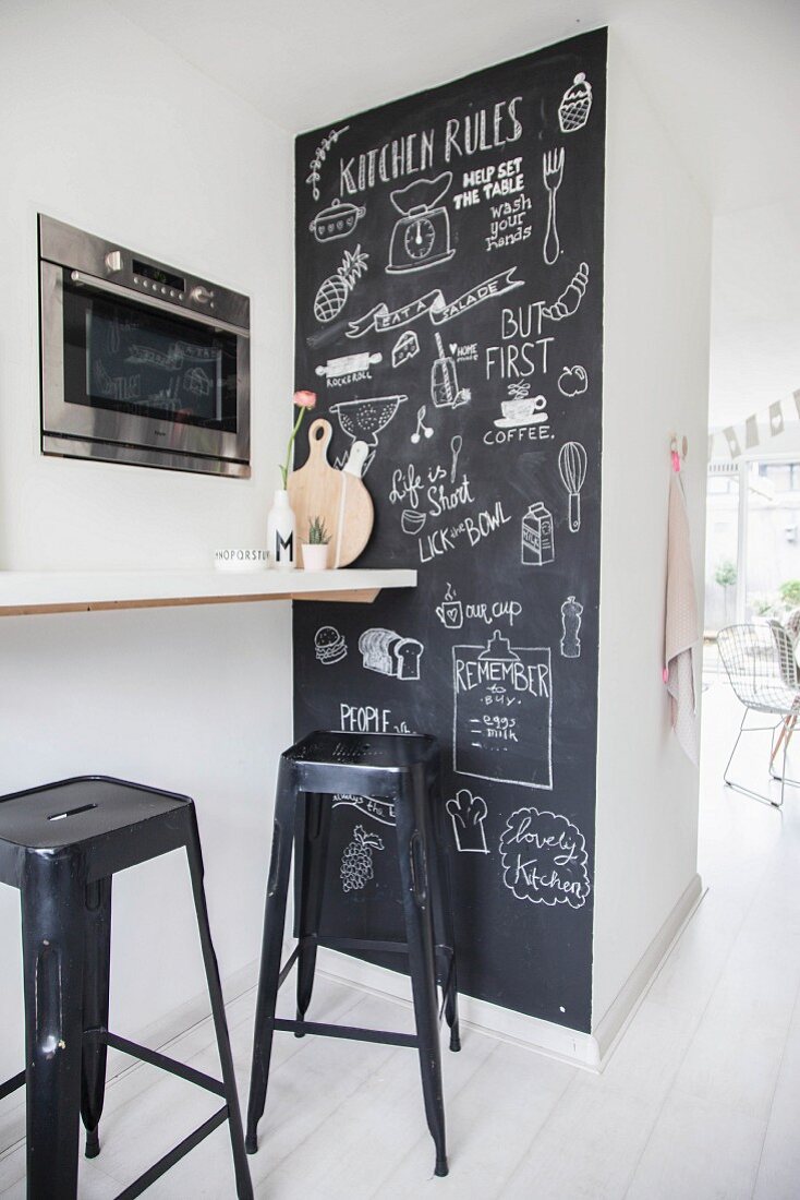 Beschriftete Tafelwand neben Frühstückstheke mit Barhockern