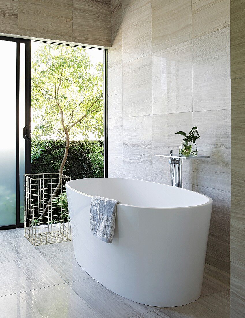 Modern free-standing bathtub with view into garden